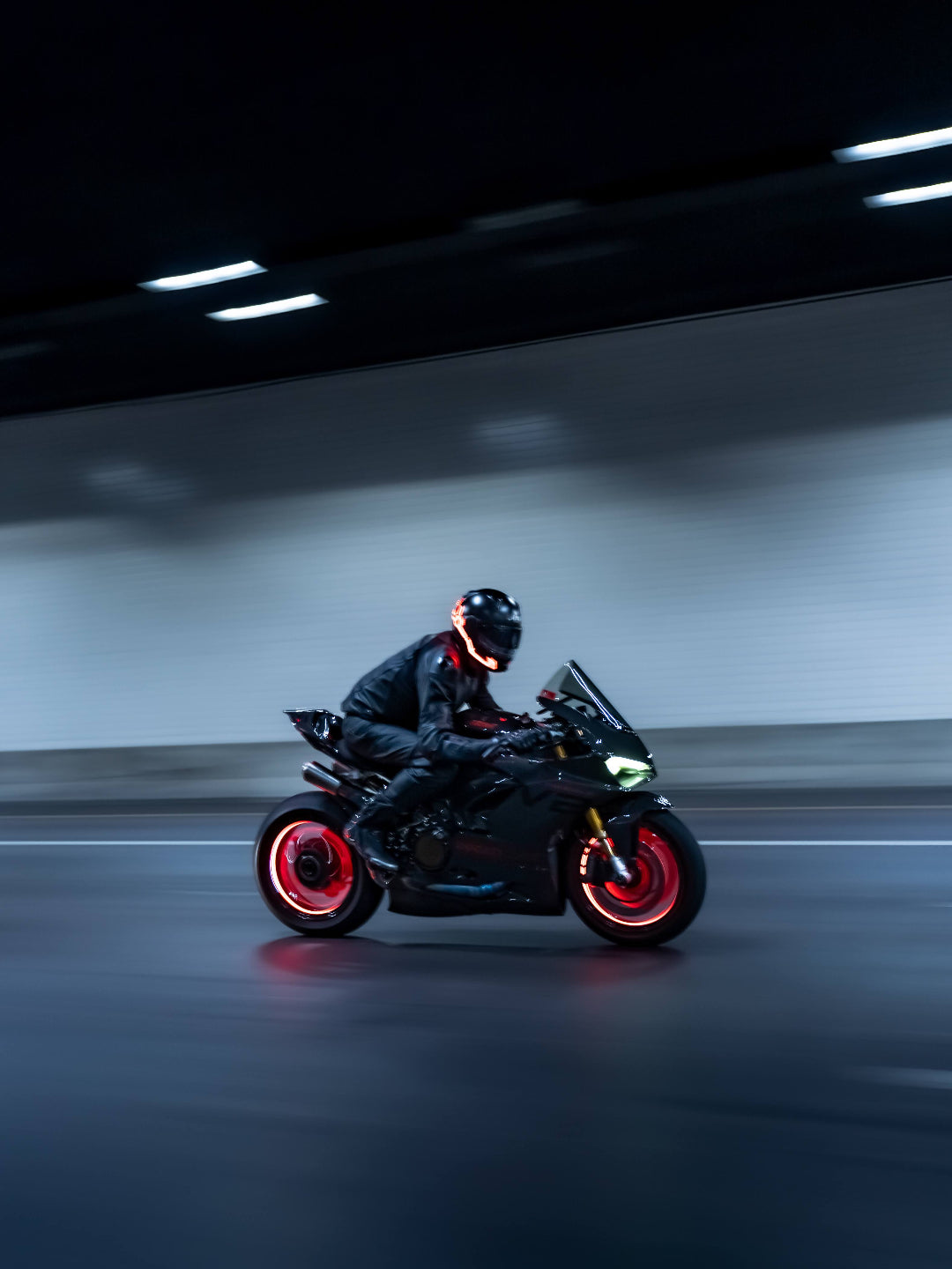 Person riding a motorcycle with glowing red wheels in a dark tunnel.