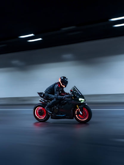 Person riding a motorcycle with glowing red wheels in a dark tunnel.