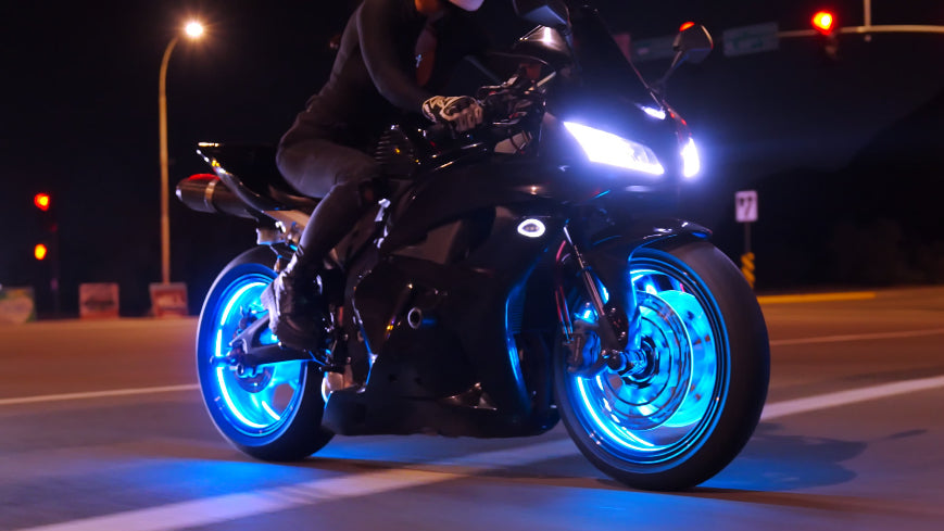 Motorcycle with glowing blue wheels on a dark street at night